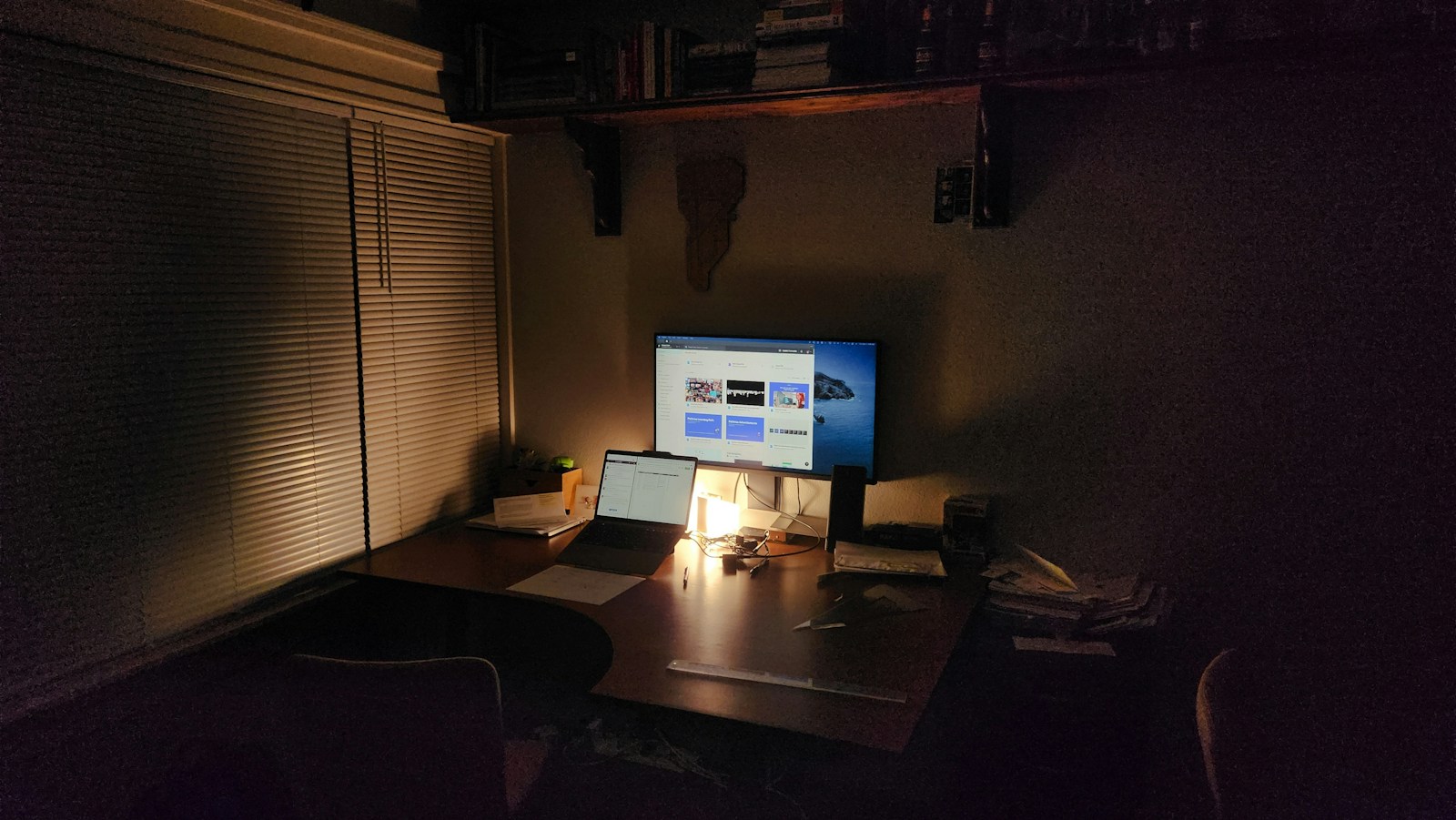 A warmly lit workspace with a laptop and monitor at night